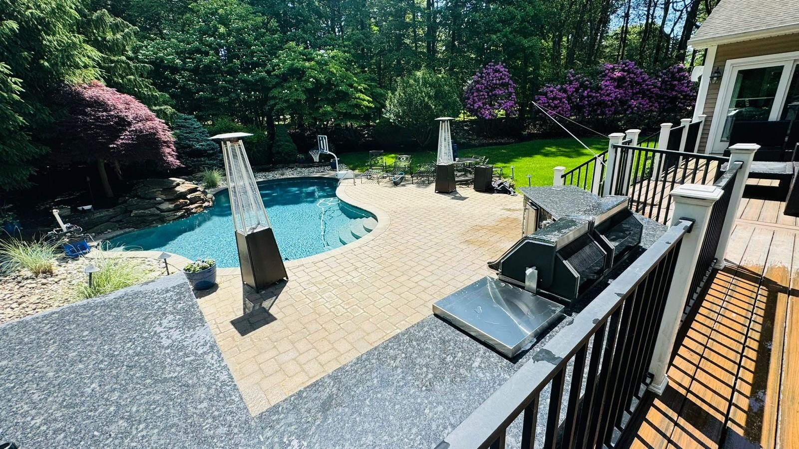 Custom pool deck and paver patio with stone outdoor kitchen built by Tavares Construction Inc